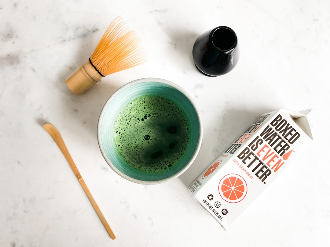 a-cup-of-green-tea-next-to-a-box-of-orange-juice-zahrut1g3qa